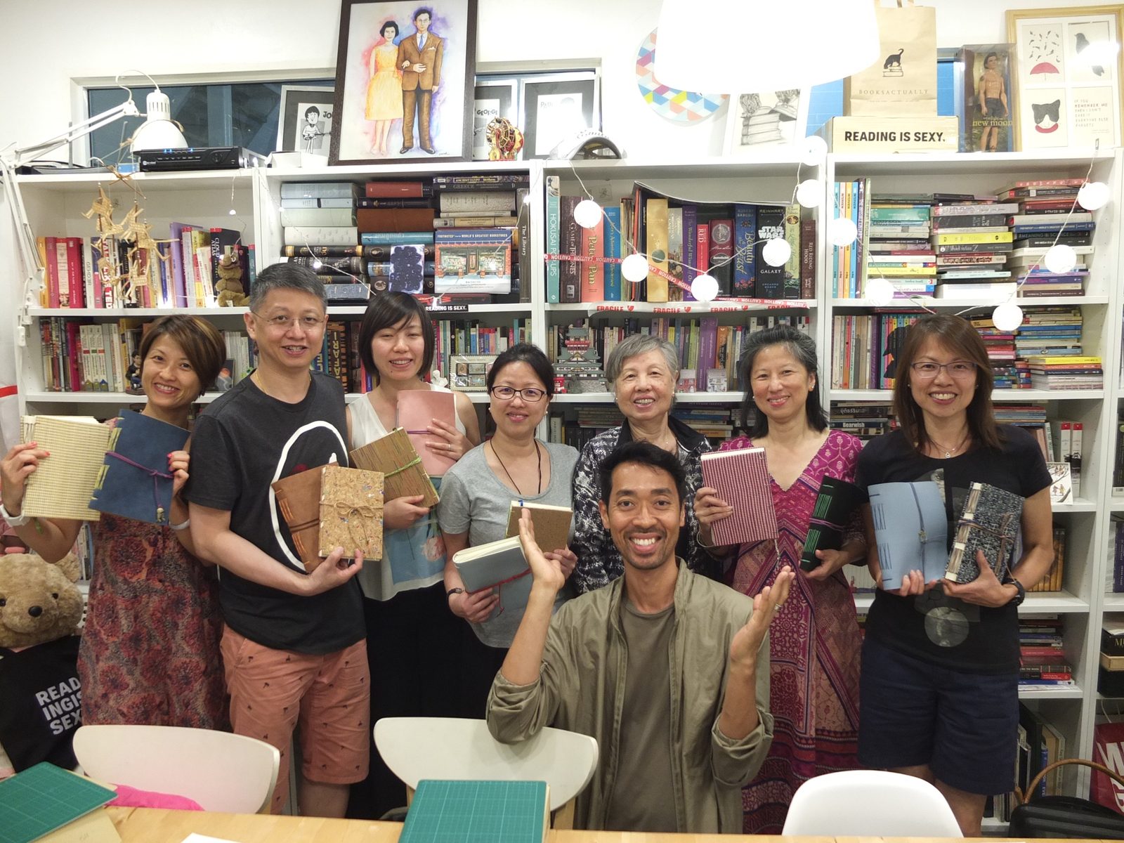Students and their instructor holding the handmade journals they bound in a Siam Bindery workshop