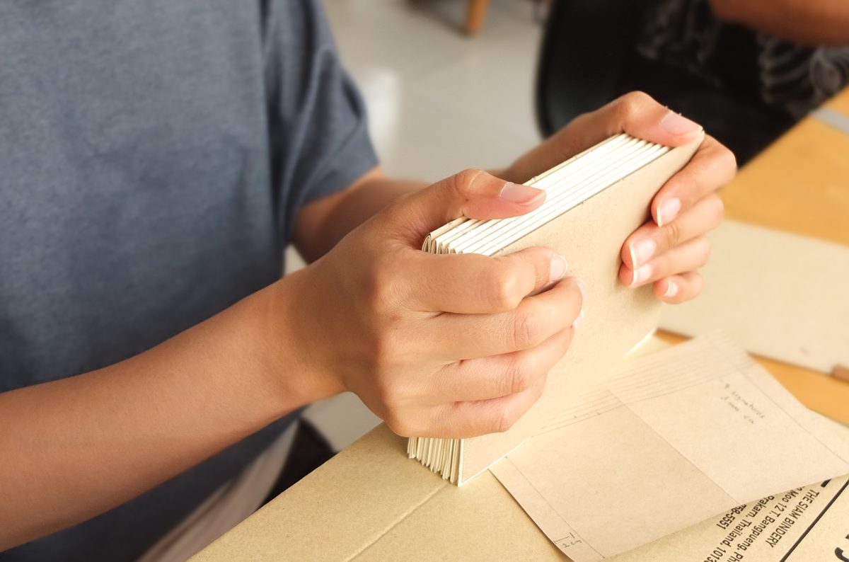 Hands holding a finished handbound softcover journal